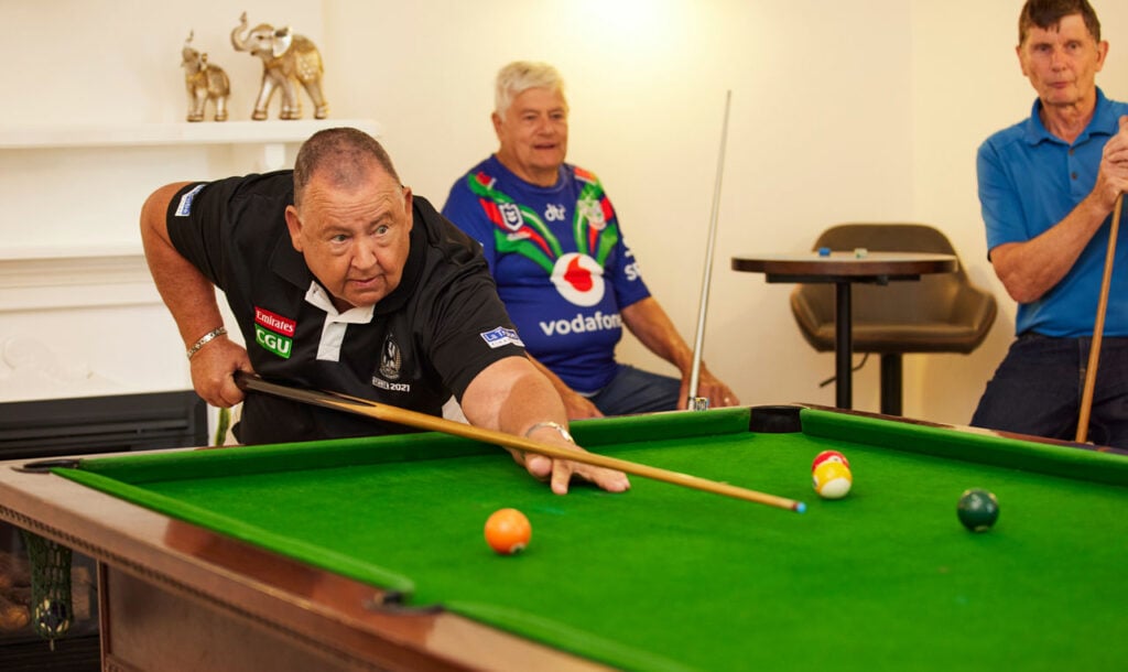 Older men playing pool in Independent Living Village