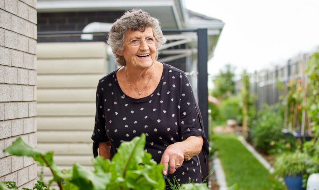 Smiling elderly woman tending to her garden at Retirement Village in Rotorua